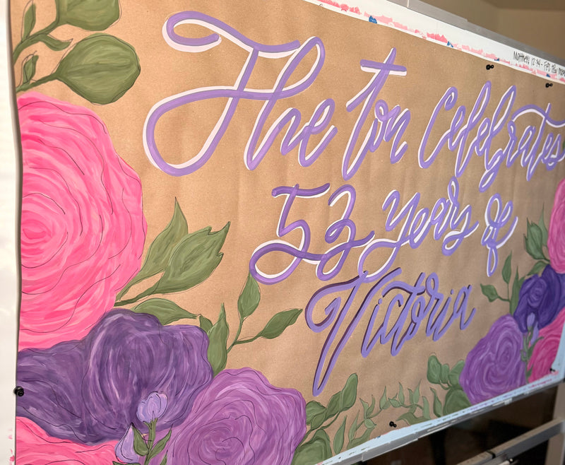 Decorative banner with floral designs and cursive text on a beige background